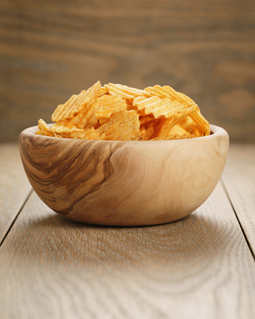 rippled potato chips with paprika in wooden bowl, with copy space