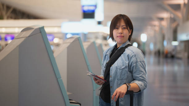 portrait of female tourist using automated self check-in counter in airport - airport airport check in counter ticket ticket machine imagens e fotografias de stock