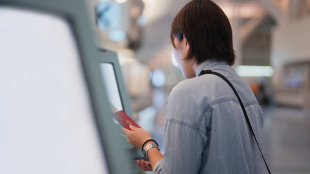 female tourist using automated self check-in counter in airport - airport airport check in counter ticket ticket machine imagens e fotografias de stock