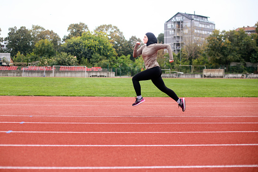 Middle-eastern female running on a track. About 25 years old, Arab woman.