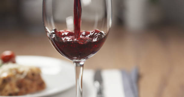 istock pouring red wine in glass with lasagna at background 1503297441