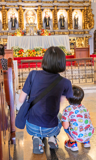 Cebu City,Cebu,Philippines-January 17 2023:Respectfully squatting low on the aisle floor,before the reveared altar of Cebu's oldest church,founded by the Spanish in 1565.