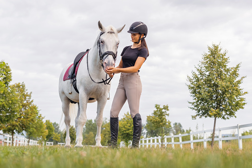 Young female horsewoman petting and bonding with her horse outside in nature