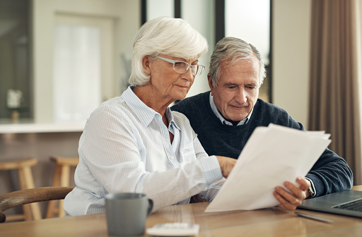 Retirement, life insurance paperwork and old couple with policy and planning with security and finance. Savings, bills and budget, elderly woman and man at home with legal documents and pension plan