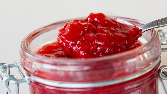 Preparation and preservation of strawberry jam in a glass jar, close up.