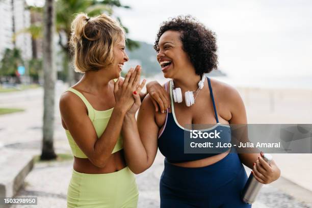 Fitness Women Laughing And Highfiving After A Beach Workout Stock Photo - Download Image Now