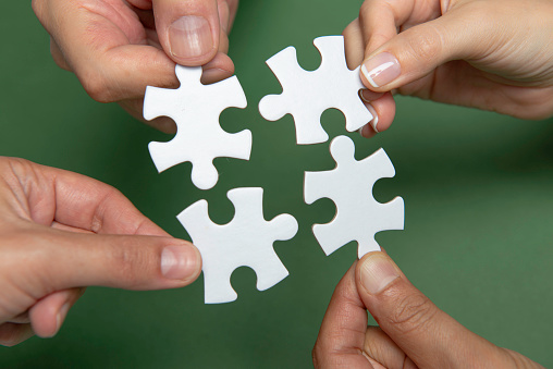 Hands holding puzzle pieces on yellow background.
