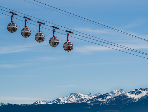 Gondola bubbles against the blue sky and the French Alps in the background. Cable car taking tourists to Fort de La Bastille in Grenoble, France