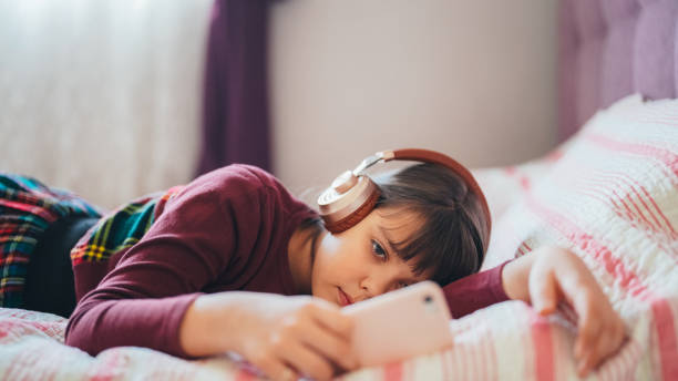Kid in bed watching viral videos on smartphone stock photo