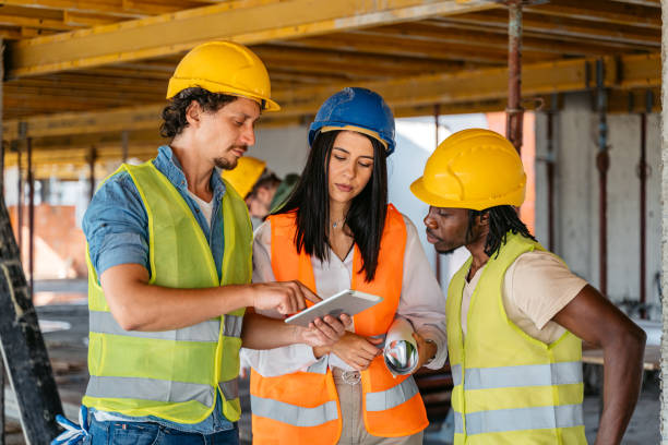 istock Female Engineer Showing The Blueprint On A Tablet To The Construction Workers On A Construction Site 1503311331