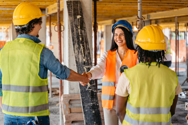 женщина-инженер пожимает руку строителю на строительной площадке - construction construction site handshake built structure стоковые фото и изображения