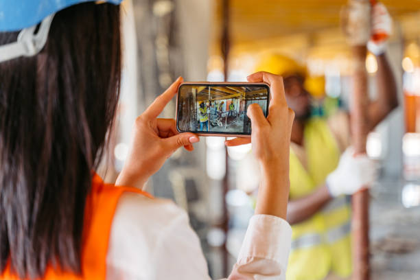 istock Female Engineer Taking Pictures Of The Construction Workers On A Construction Site 1503314888