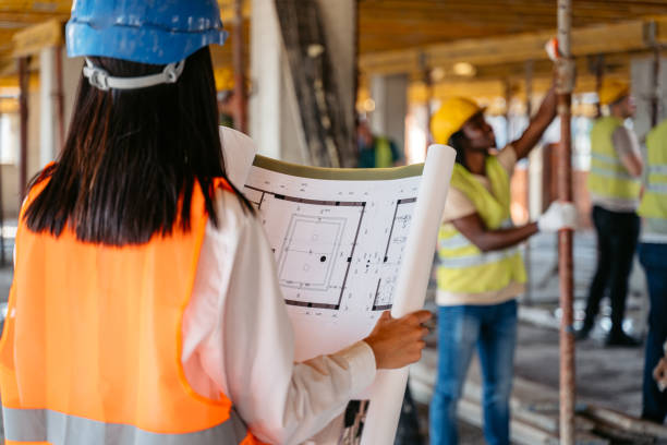 female engineer looking at the blueprint on a construction site - subcontractor imagens e fotografias de stock