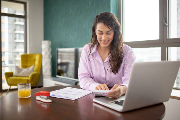 istock Young woman using calculator while going through bills and home finances 1503315245