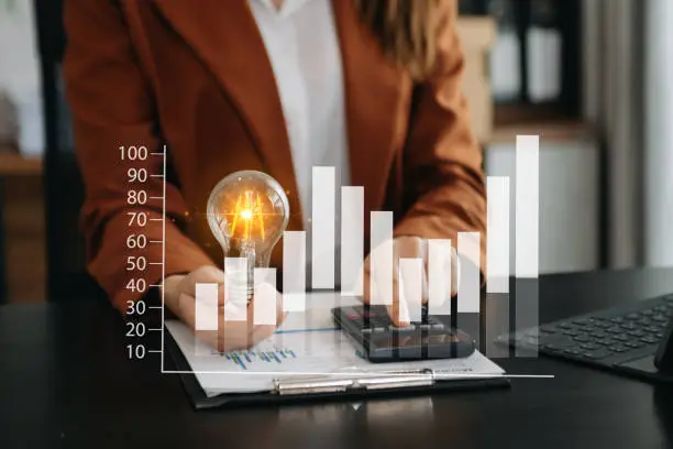 Photo of Businesswoman holding and putting lightbulb on coins stack on table for saving energy and money concept
Idea saving energy and accounting finance concept