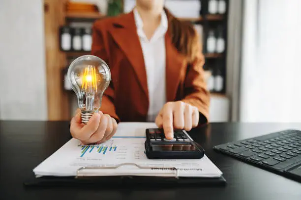 Photo of Businesswoman holding and putting lightbulb on coins stack on table for saving energy and money concept
Idea saving energy and accounting finance concept