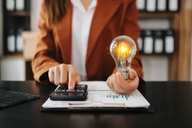 Photo of Businesswoman holding and putting lightbulb on coins stack on table for saving energy and money concept
Idea saving energy and accounting finance concept