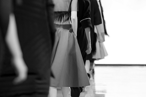 A grayscale shot of fashion models walking the catwalk during a fashion show.