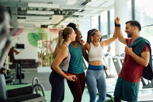 We did it, it was a great workout! Happy athletic friends congratulating each other on successful sports training in a gym. community health center stock pictures, royalty-free photos & images