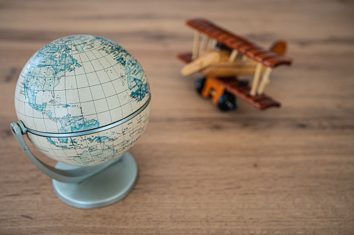 Globe and wooden airplane on wooden background. Travel concept.