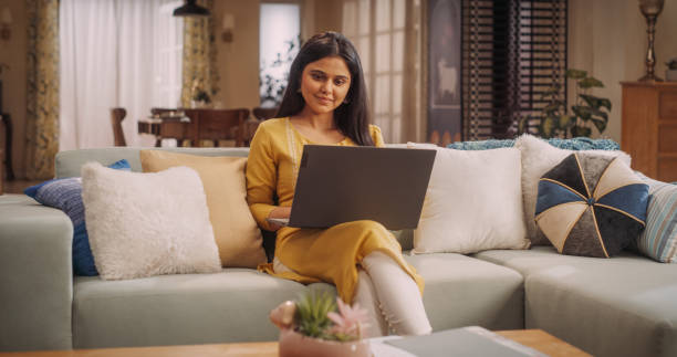 istock Beautiful Indian Woman Using Laptop at Home, Focused on Remote Work Tasks and Managing Team. She Enjoys Online Shopping, Exploring Sales and Discounts to Find Perfect Clothing Deals. Medium Shot 1503328753
