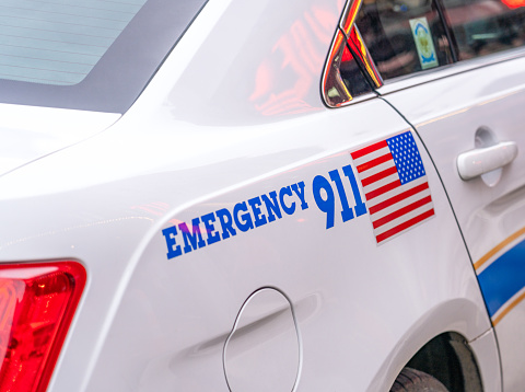 The emergency number 911 printed on the side of a police car in the USA.