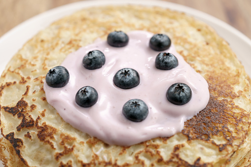 blini or crepes with yogurt and blueberries closeup, sweet breakfast