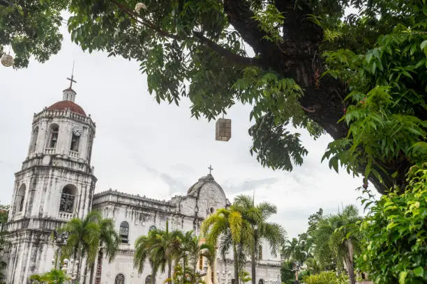Spanish colonial architecture and domed bell tower.Palm trees line the gardens outside the Cathedral and lampshades hang from a large tree.