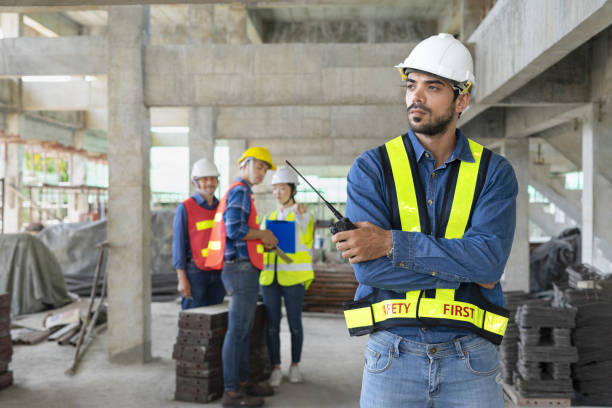 young confident engineer with arms crossed,holding walkie talkie background group of colleagues talking and bullying him