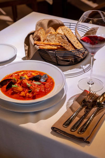 istock Tomato soup with seafood in a light ceramic plate. The soup is on a table with a light tablecloth, next to it is a glass of red wine and cutlery. 1503345713