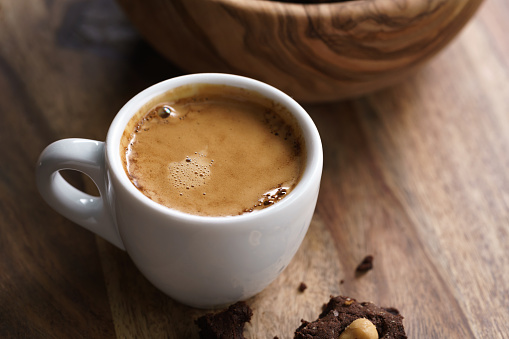 cup of fresh espresso with homemade chocolate cookie with hazelnuts, shallow focus