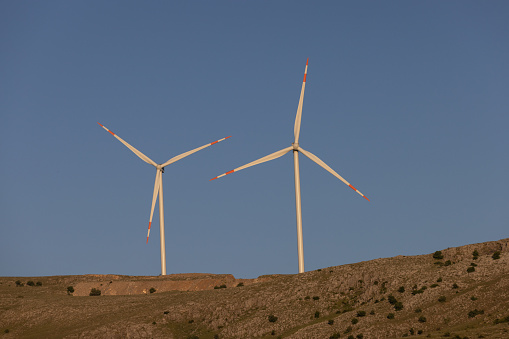 Multiple wind turbines in nature at sunset.