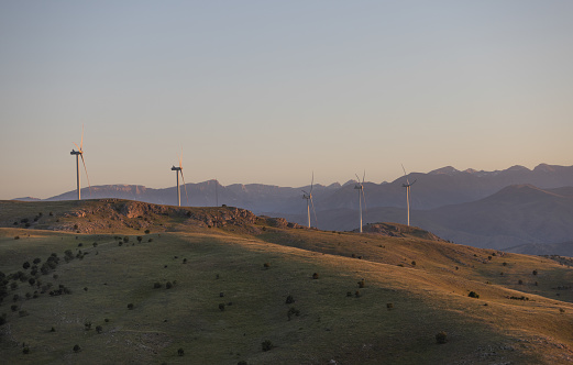 A group of wind turbines on top of the mountain at sunset.