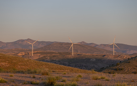 Wind power plant on the top of the mount at sunset.