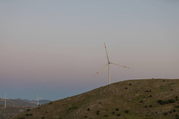 A group of wind turbines on top of the mount at sunset.