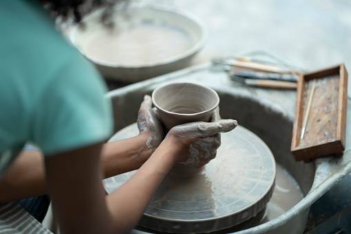 With tender care and determination, an African American boy nurtures his clay artistry, shaping and molding clay with precision and creativity in the supportive ceramic workshop.