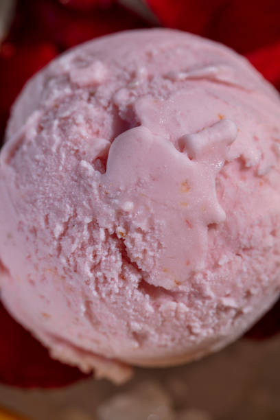 On a round, white plate are 6 balls of different types of ice cream and ice cream in chocolate on a stick. Ice cream lies on a small ice crumb, berries lie nearby. The plate is on a white tablecloth.