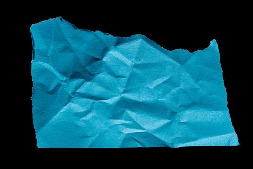 Rip blue paper piece isolated on a black background. Ripped or torn paper, design element.
