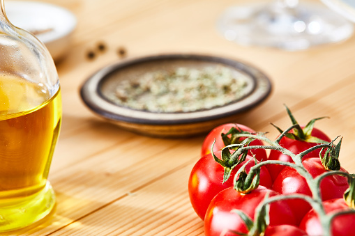 Food backgrounds: olive oil, herbs and spices arranged at the right of a wooden table leaving useful copy space for text and/or logo at the left. Predominant colors are yellow, green and brown. XXXL 42Mp studio photo taken with Sony A7rii and Sony FE 90mm f2.8 macro G OSS lens