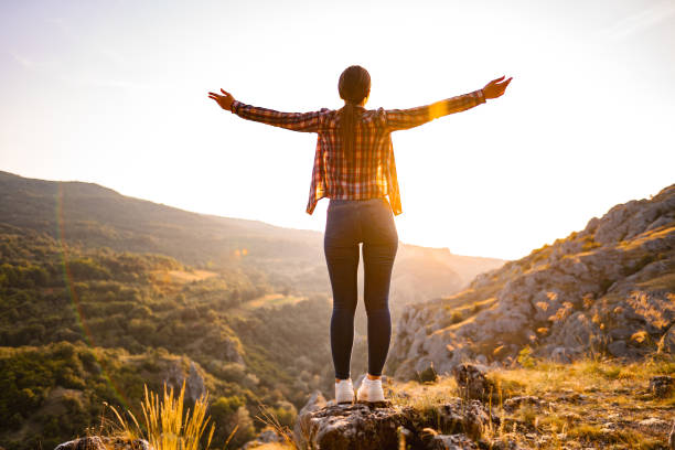istock Young woman standing on mountain peak looking at sunset 1503363200