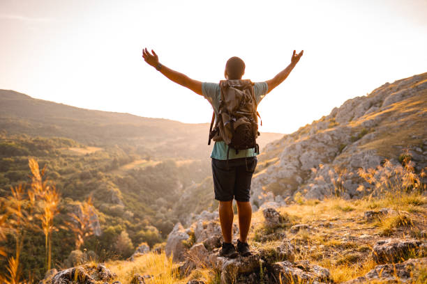 istock Young man standing on mountain peak looking at sunset 1503363211