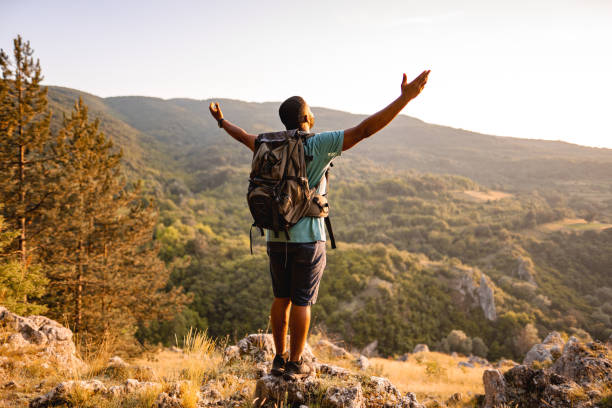istock Young man standing on mountain peak looking at sunset 1503363312