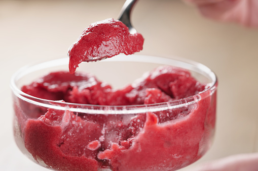 eating raspberry sorbet ice cream with spoon closeup, shallow focus