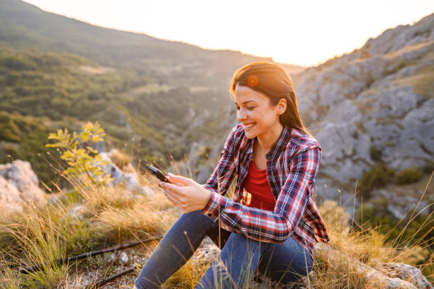 istock Young woman using phone on a mountain peak with wonderful view 1503363504