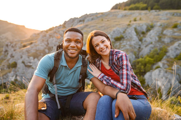 istock Happy multiracial couple sitting on mountain peak 1503364156