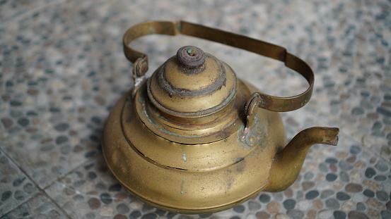 an old copper coffee pot that is heavily scratched and dusty.