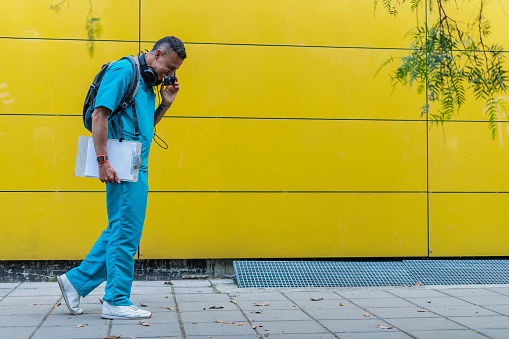 Latino nurse from Bogota Colombia between 40 and 44 years old, walks down the street in his work uniform
