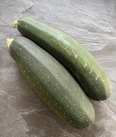 Green fresh organic zucchinies on the gray stone texture