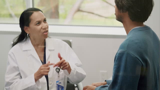 Male patient uses sign language to discuss arm pain with doctor