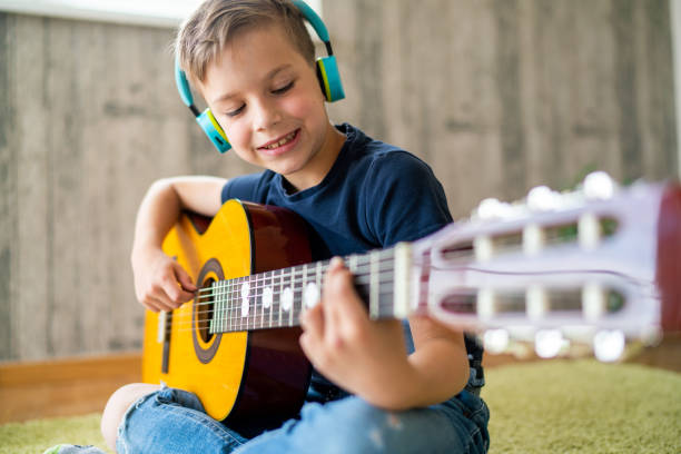 istock Smiling little boy playing acoustic guitar at home 1503374881